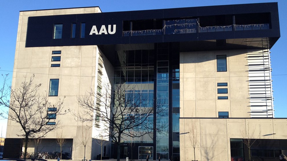 AAU Biotek med sin gule facade og en markant udbygning i sort på øverste etage med AAU skrevet i store hvide bogstaver