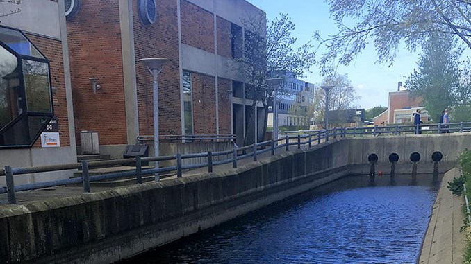 Kanal langs med Aalborg Universitet. I gangbroen over kanalen ses fire gennemgående røråbninger