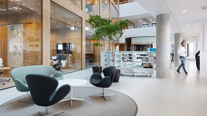 Bygningsstyrelsens kontor i København. I forgrunden ses to stole og en sofa til korte snakke. I baggrunden ses en hvid reol og kig ind gennem ruderne til mødelokaler