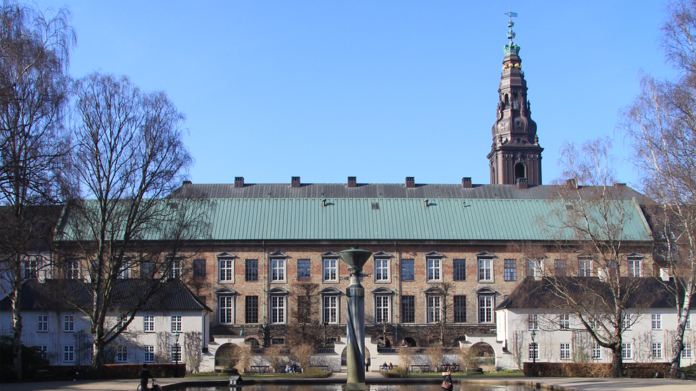 Rigsarkivets tidligere bygning i Rigsdagsgården set fra parken bag ved med tårnet på Christiansborg der syner i baggrunden