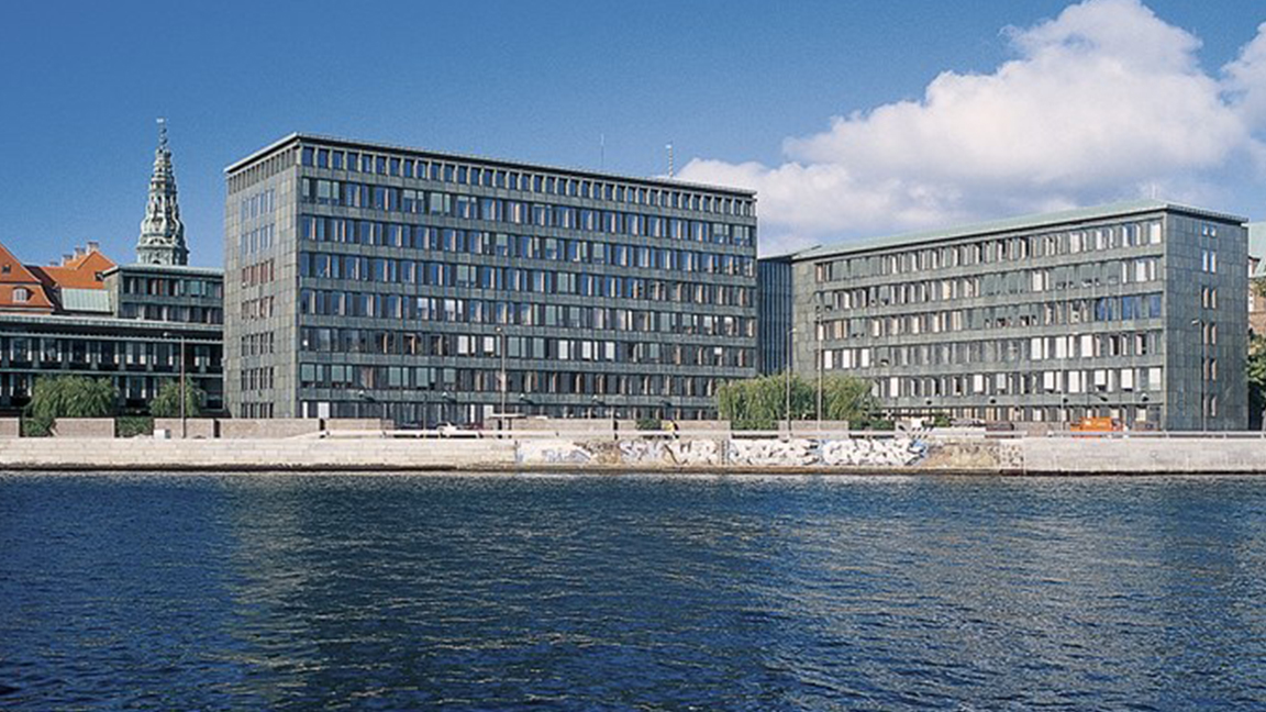 Ministeriebygningerne i Slotsholmsgade med tårnet på Christiansborg Slot i baggrunden set fra den modsatte side af havnen.