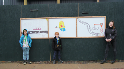 De tre vindere af tegnekonkurrencen ved Kulturnatten 2015 hos Bygningsstyrelsen foran deres tegninger på det grønne byggepladshegn