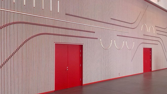 Kunst på Syddansk Universitet, Campus Kolding, af kunstner Tobias Rehberger. Mønster af tynde lysstof i røde og hvide farver på en væg af trælameller med to markante røde døre.