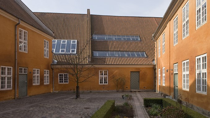 Baggården til Frederiksholms kanal 21-23. Bygningernes facader er kalkede i en orange farve, mens vinduerne er malet hvide.