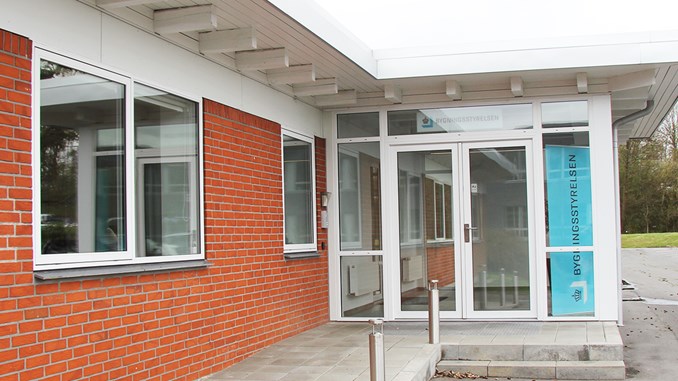 Hovedindgangen til Bygningsstyrelsens kontor i Skanderborg med Bygningsstyrelsens logo i fuld højde i vinduet