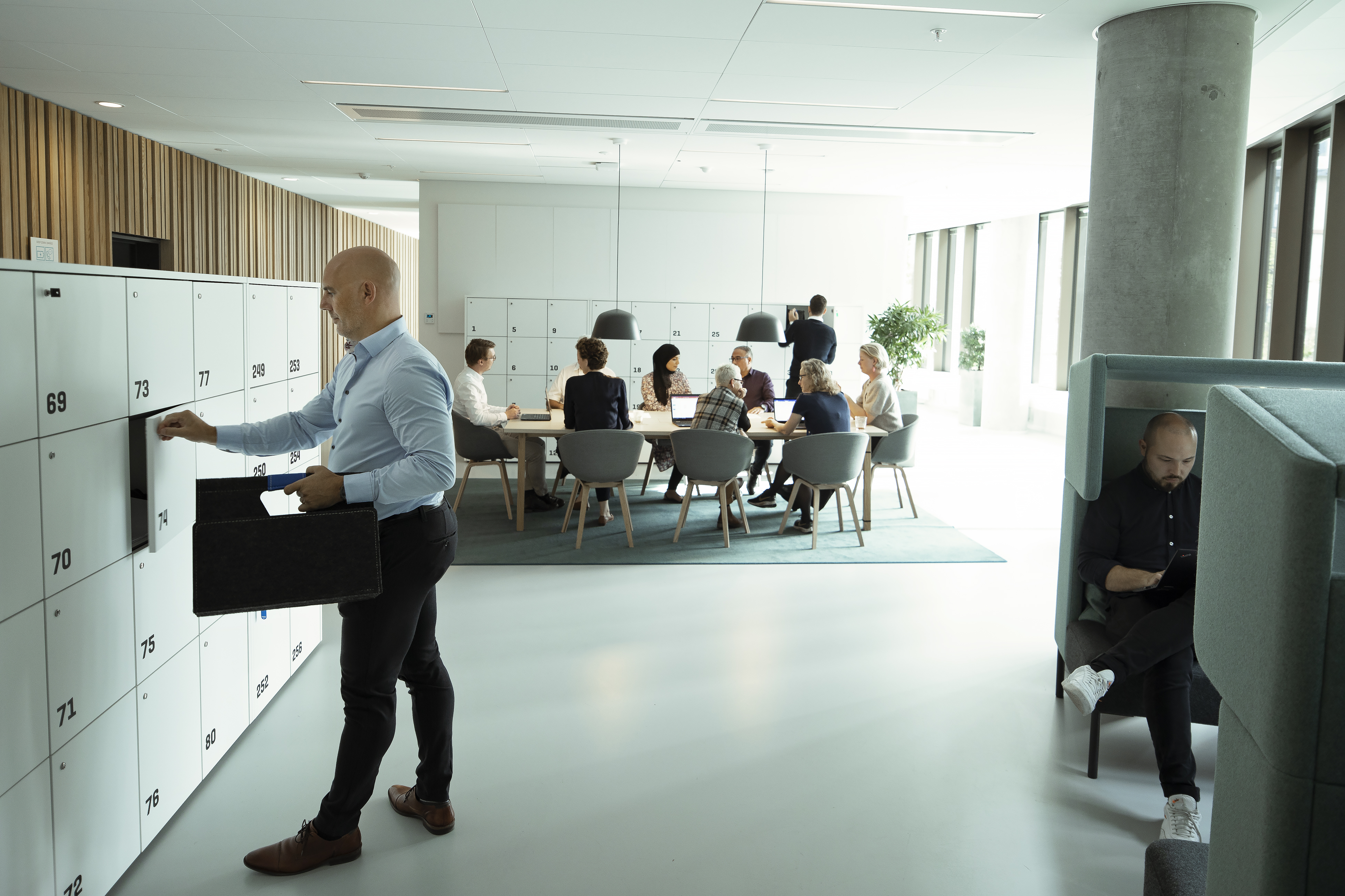 Bygningsstyrelsens kontor i København. I forgrunden ses to stole og en sofa til korte snakke. I baggrunden ses en hvid reol og kig ind gennem ruderne til mødelokaler